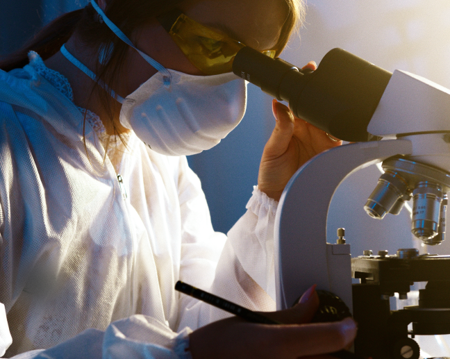 scientist wearing mask and looking into microscope