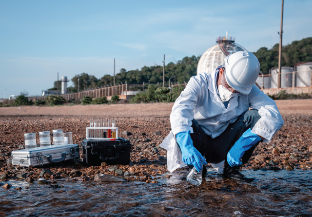 Scientist wearing protective uniform and gloves collecting marine water samples