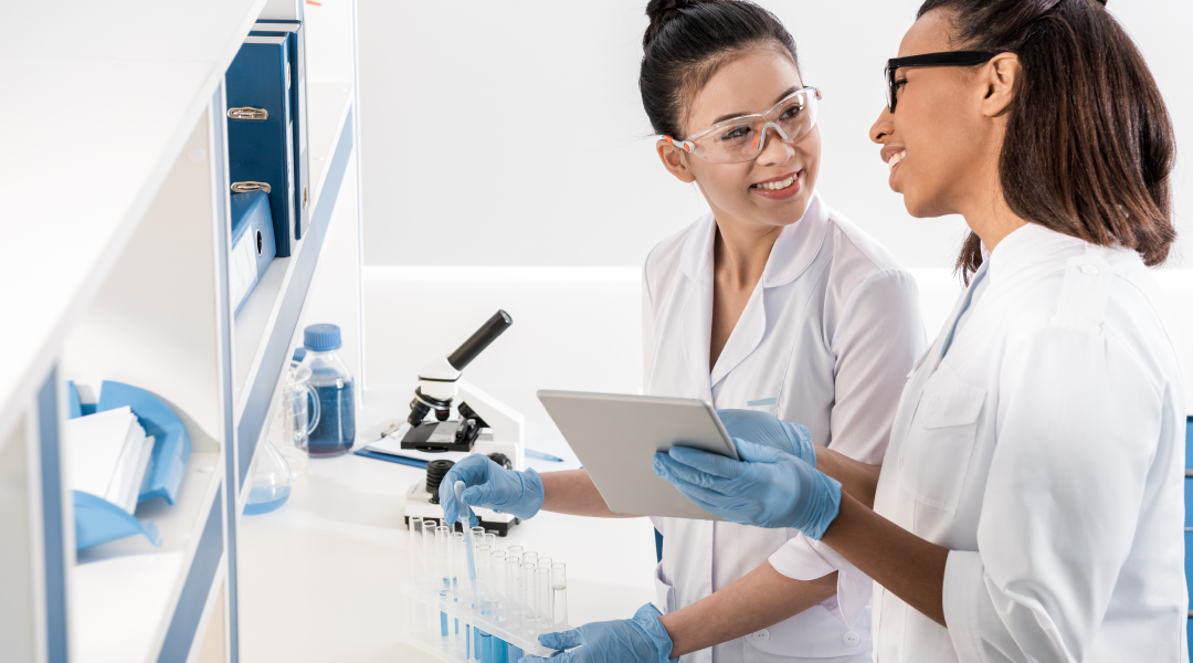 female scientists looking at data on eln while filling test tubes