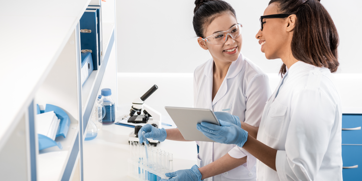 female scientists looking at data on eln while filling test tubes