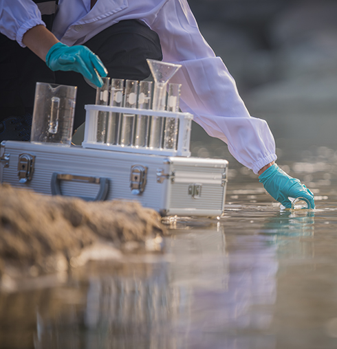 scientist wearing protective uniform and gloves collecting water samples for marine monitoring